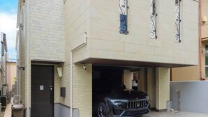 Un edificio moderno de dos pisos con un garaje y un coche negro estacionado en su interior.