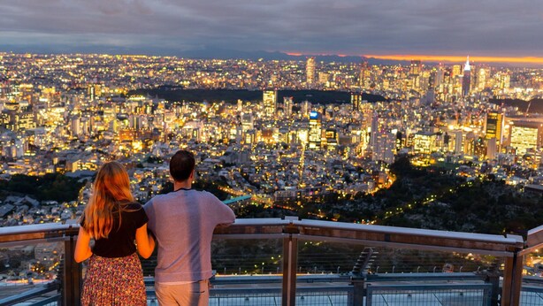 Una pareja observa un paisaje urbano con numerosos edificios y luces.