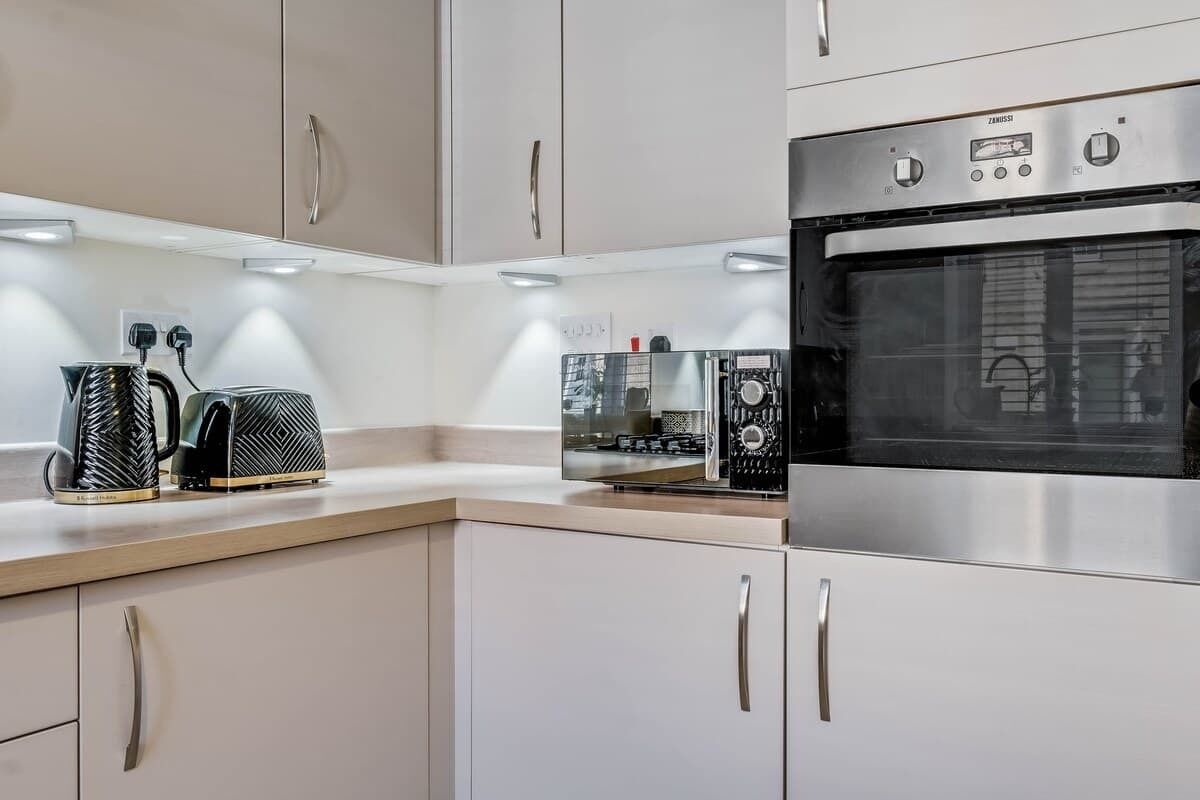 A modern kitchen with stainless steel appliances, including an oven and a coffee maker.