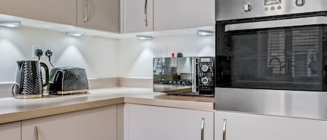A modern kitchen with stainless steel appliances, including an oven and a coffee maker.