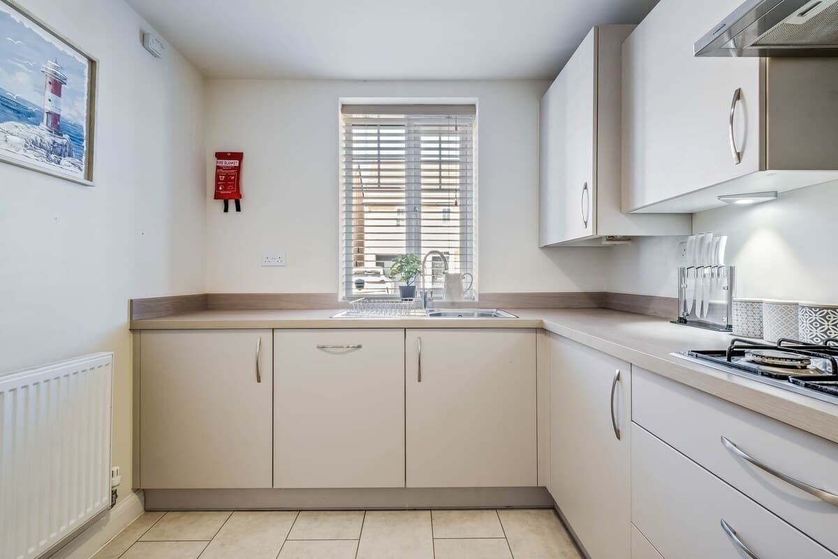 A kitchen with a window, a fire extinguisher, and a stove.