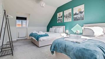 A bedroom with two beds, a radiator, a window, and artwork on the wall.