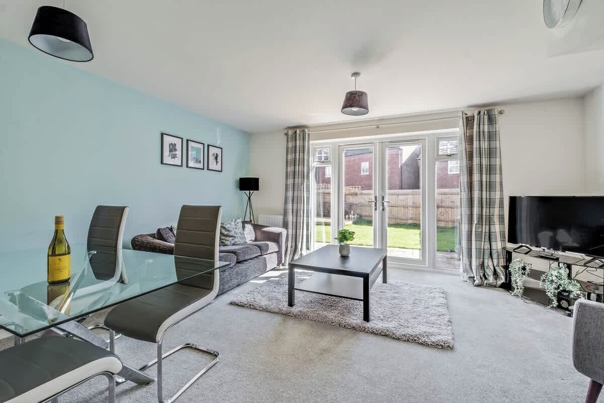 A modern living room with a glass dining table, sofa, and television.