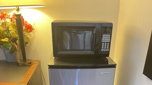 A compact kitchenette with a refrigerator, a microwave, and a small countertop. - Branson Victorian Inn (Branson)