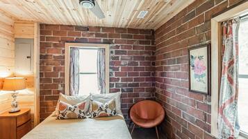 A room with a bed, a chair, a window, and a ceiling fan.