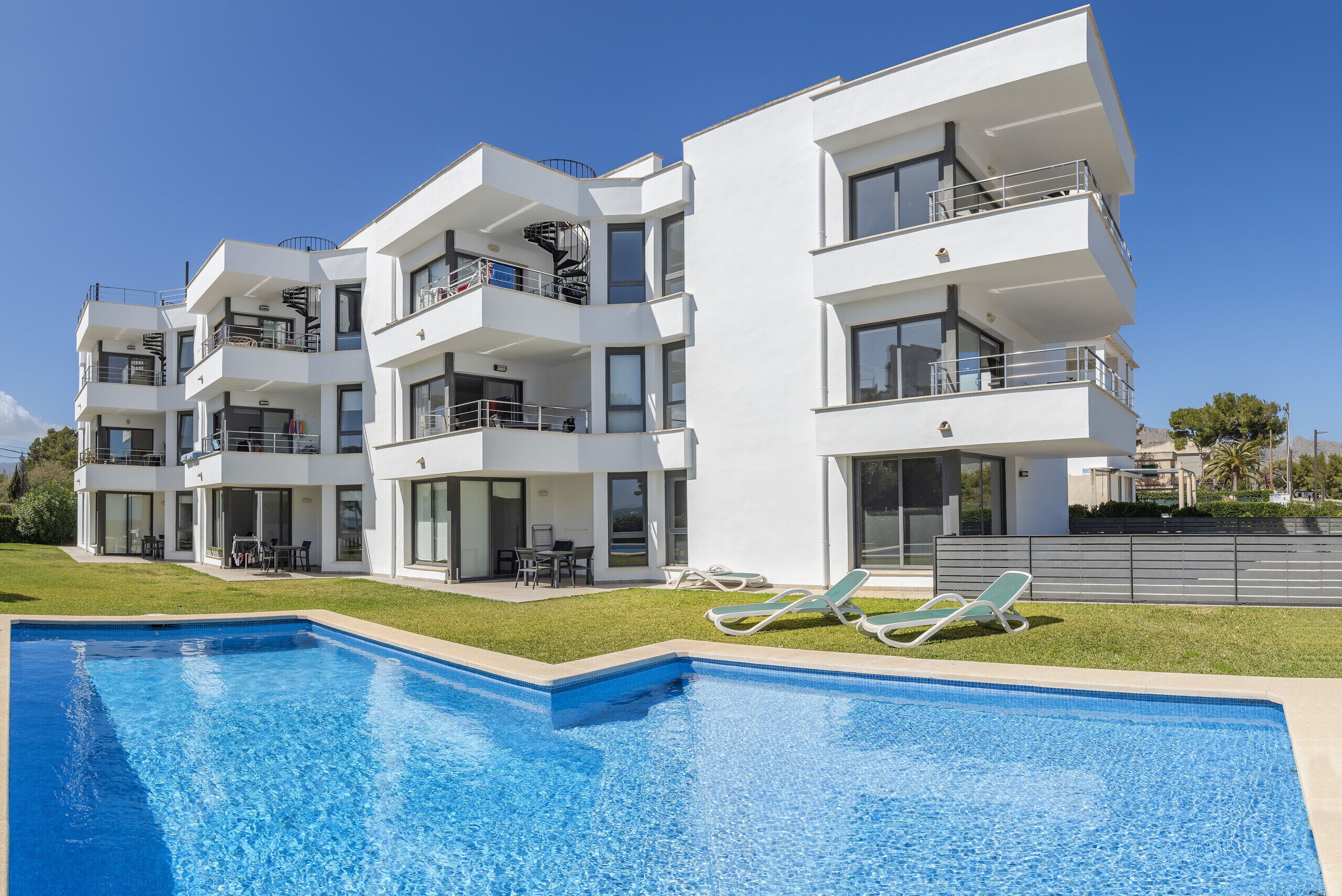 Un moderno edificio residenziale a più piani con piscina e area salotto esterna.