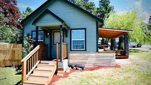 A single-story house with a porch, a covered patio, and a wooden deck. - 2BR Cabin • 5 Min to Autzen • Park Access • Pet Friendly (Springfield)