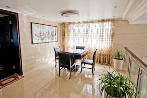 A dining area with a table and chairs, a potted plant, and a window with curtains. - Yandangshan Yunshuijian Homestay (Yueqing)