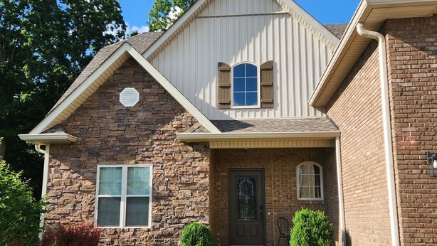 A two-story house with a stone facade, a front porch, and a well-maintained lawn. - Southern Belle (Clarksville)