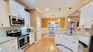 A modern kitchen with white cabinets, stainless steel appliances, and a wooden floor. - Southern Belle (Clarksville)