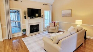 A living room with a fireplace, a sofa, a television, and a lamp. - Southern Belle (Clarksville)