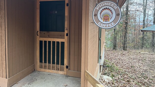 A wooden door with a glass panel and a sign reading "PIONEER COFFEE". - Entire Campground - All 10 Cabins for Events and Overnights. Up to 40 Guests. (Hatfield)