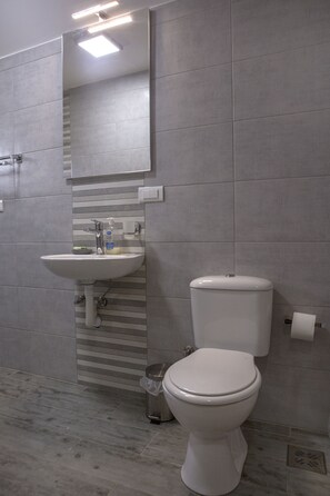Een moderne badkamer met een wit wastafel, toilet en spiegel.