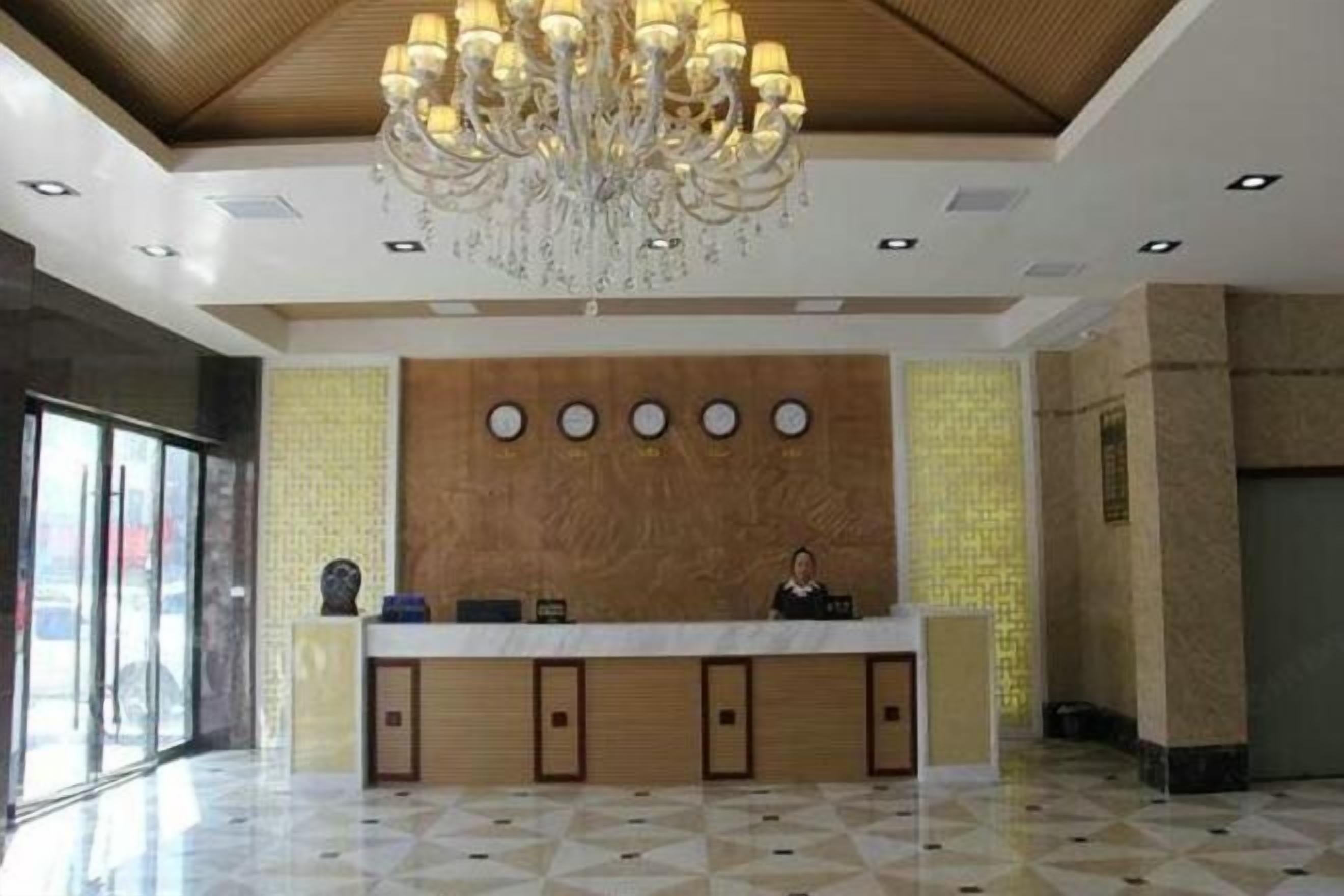 A reception area with a wooden reception desk, a chandelier, and a patterned floor.
