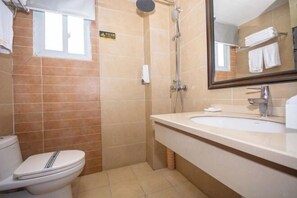 A bathroom with a toilet, a shower, and a sink with a mirror. - Yuhuangge Hotel (Badong)