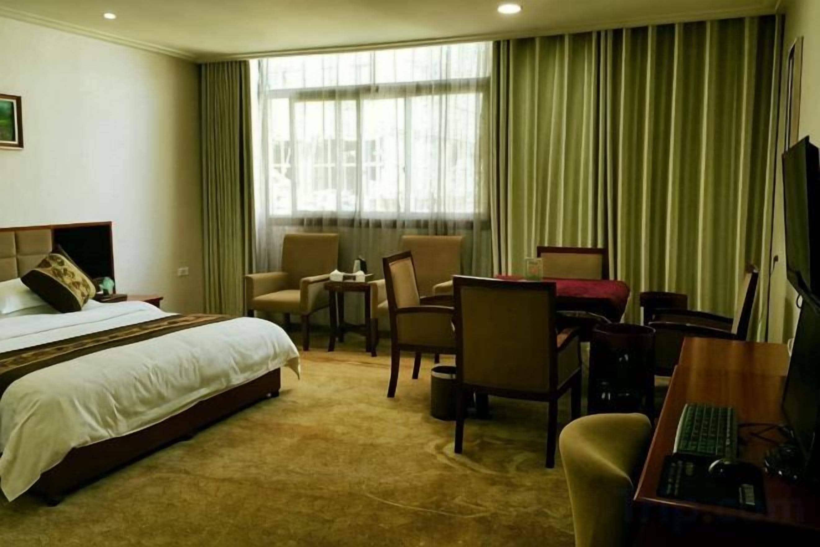 Une chambre d’hôtel avec un lit, un bureau, une chaise et un téléviseur.