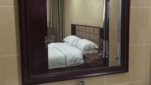 Una habitación de hotel con una cama, un espejo y una puerta.