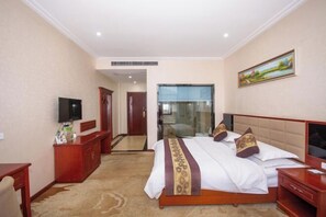 A hotel room with a bed, a TV, a desk, and a mirror. - Yuhuangge Hotel (Badong)