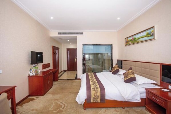 A hotel room with a bed, a TV, a desk, and a mirror. - Yuhuangge Hotel (Badong)