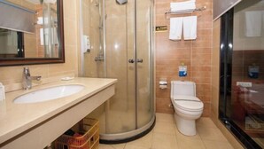 Un baño con ducha de mampara de vidrio, un lavabo e inodoro.