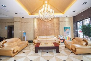 A lobby with a chandelier, sofas, a coffee table, and a large poster. - Yuhuangge Hotel (Badong)