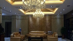 Un hall con candelabro, sofás de cuero y suelo estampado.