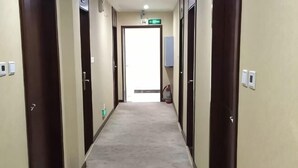 Un pasillo alfombrado con puertas a ambos lados, que conduce a una salida luminosa.