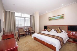 A hotel room with a large bed, a desk, a chair, and a television. - Yuhuangge Hotel (Badong)
