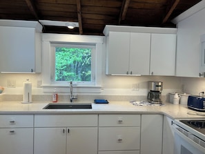 A modern kitchen with white cabinets, a stainless steel sink, a coffee maker, and a toaster.