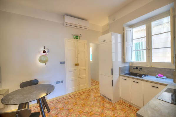 A compact kitchen with a sink, a small dining table, and a patterned floor.