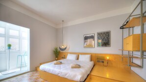 Ein modernes Hotelzimmer mit einem großen Bett, einem kleinen Balkon und Blick auf die Stadt.