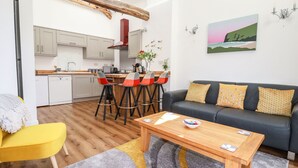 A modern living space with a kitchen, a dining area with bar stools, a sofa, and a coffee table.