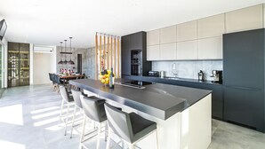 A modern kitchen with a large island, bar stools, and a dining area with a table and chairs.