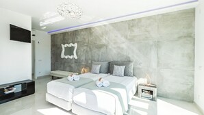 A modern bedroom with a large bed, a TV, and a built-in heater.