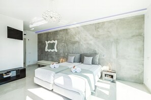 A modern bedroom with a large bed, a TV, and a stone accent wall.