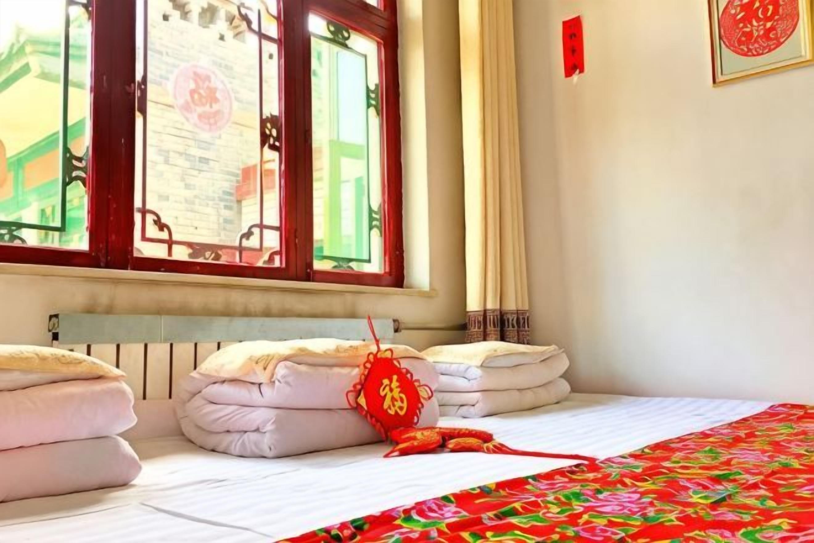 A hotel room with a bed, a window with a view, and a red decoration on the bed.