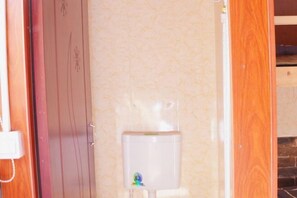 A bathroom with a toilet, a wooden door, and a tiled wall. - Sanyuesan International Youth Hostel (Pingyao County)
