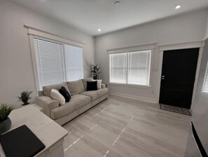 Relax in this stylish living room with a beige sofa, side table, and potted plant.