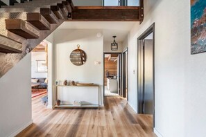 Staircase leads to an upper level, with a hallway featuring a console table and mirror.