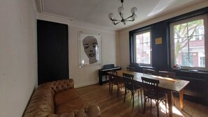 A dining area with a wooden table and chairs, a brown leather sofa, and a chandelier. - Family Friendly Funhouse Centrally Located in Ottensen (Hamburg)