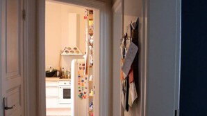 A hallway with wooden flooring leading to a kitchen area with a refrigerator and a pantry. - Family Friendly Funhouse Centrally Located in Ottensen (Hamburg)