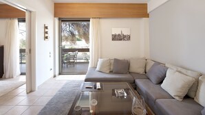 Una sala de estar moderna con un sofá seccional, una mesa de centro de vidrio y una obra de arte con un paisaje urbano en la pared.