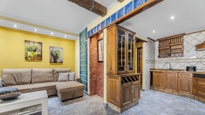 Una sala de estar con sofá, una mesa de centro y una cocina con armarios de madera y salpicadero de azulejos.