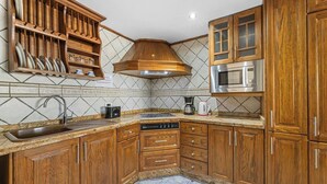 Una cocina con armarios de madera, microondas integrado, lavaplatos y estufa.
