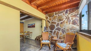 Un comedor con paredes de piedra, vigas de techo de madera y mobiliario de mimbre.