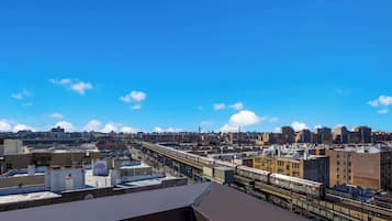 Un immeuble de grande hauteur doté d’une terrasse sur le toit, d’où l’on peut admirer la vue sur la ville et les voies ferrées.