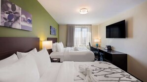 A hotel room with two beds, a desk, a TV, and artwork on the walls. - Sleep Inn Bronx - Soundview (Bronx)