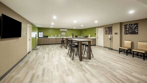 A spacious room with a long table and multiple stools, a flat-screen TV mounted on the wall, and a reception desk. - Sleep Inn Bronx - Soundview (Bronx)