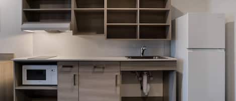 A modern kitchen with built-in wooden cabinets, a microwave, a sink, and a refrigerator.