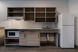 Una cocina moderna con armarios de madera, microondas integrado, pileta y refrigerador blanco.